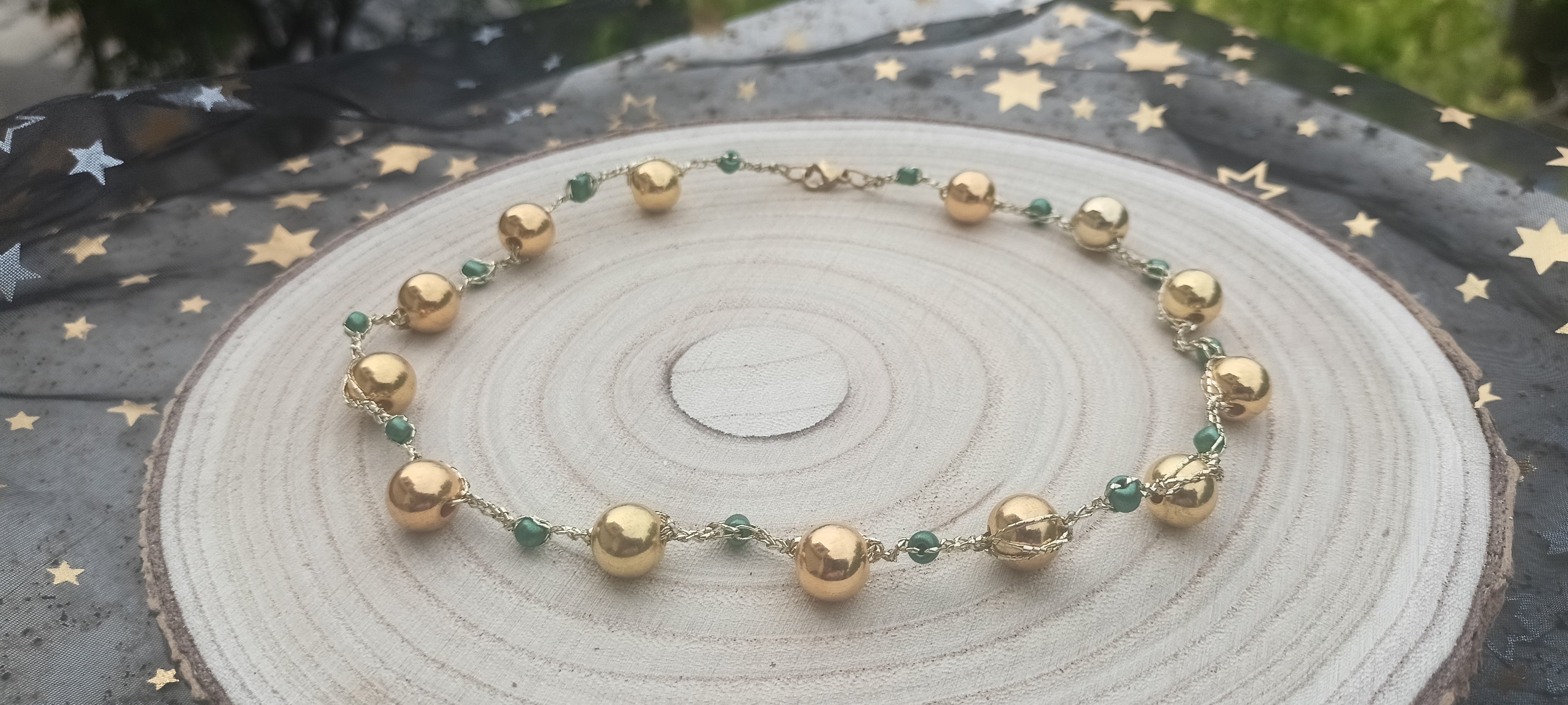 Gargantilla Oro de Oriente sobre madera natural con fondo de estrellas